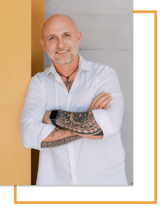 A portrait of Rob DuBois wearing a white shirt. He has his arms crossed and is smiling at the camera.